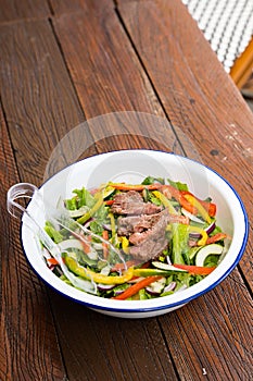 Gourmet mixed garden salad with red onion, bell peppers, zucchini and steak