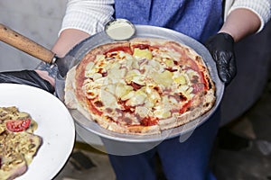 Gourmet pizza with barbeque sauce, grilled chicken, cheese served by waiter in restaurant or diner