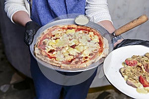 Gourmet pizza with barbeque sauce, grilled chicken, cheese served by waiter in restaurant or diner