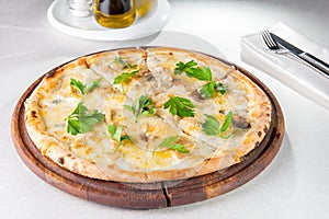 gourmet pizza with gorgonzola and porcini white mushrooms decorated with parsley leaves on the wooden board on the served