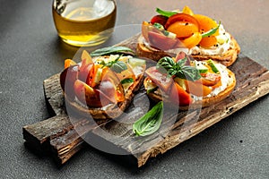 Gourmet sandwiches bread toast, bruschetta with cream cheese, peaches, tomatoes and green basil leaves
