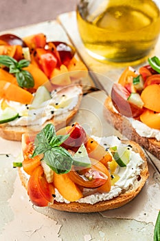 Gourmet sandwiches bread toast, bruschetta with cream cheese, peaches, tomatoes and green basil leaves