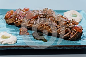 Gourmet Sliced Beef Tenderloin with Herb-Tomato Relish and Artisan Purees on Elegant Ceramic Plate photo