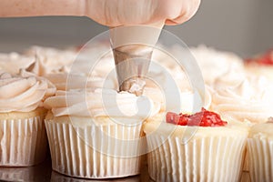 Gourmet strawberry filled cupcakes with frosting - being piped by a chef
