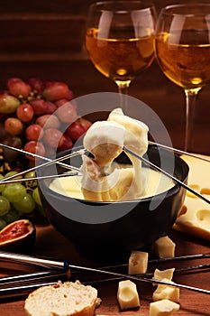 Gourmet Swiss fondue dinner on a winter evening with assorted cheeses on a board alongside a heated pot of cheese fondue