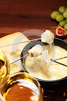 Gourmet Swiss fondue dinner on a winter evening with assorted cheeses on a board alongside a heated pot of cheese fondue