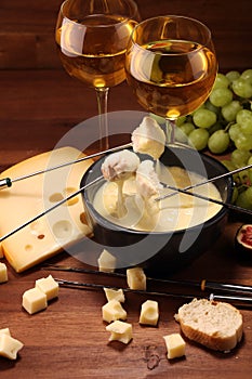 Gourmet Swiss fondue dinner on a winter evening with assorted cheeses on a board alongside a heated pot of cheese fondue