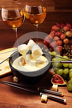 Gourmet Swiss fondue dinner on a winter evening with assorted cheeses on a board alongside a heated pot of cheese fondue