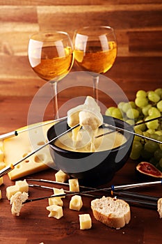 Gourmet Swiss fondue dinner on a winter evening with assorted cheeses on a board alongside a heated pot of cheese fondue