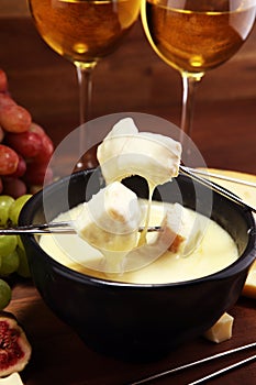 Gourmet Swiss fondue dinner on a winter evening with assorted cheeses on a board alongside a heated pot of cheese fondue