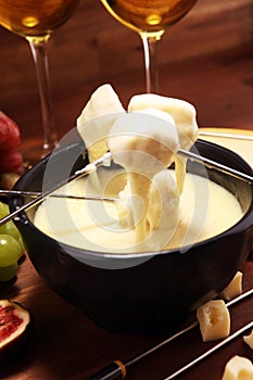 Gourmet Swiss fondue dinner on a winter evening with assorted cheeses on a board alongside a heated pot of cheese fondue