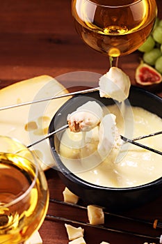 Gourmet Swiss fondue dinner on a winter evening with assorted cheeses on a board alongside a heated pot of cheese fondue