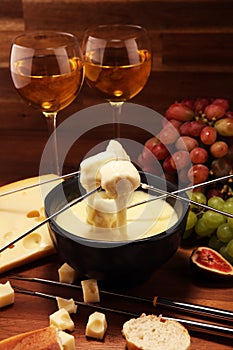 Gourmet Swiss fondue dinner on a winter evening with assorted cheeses on a board alongside a heated pot of cheese fondue