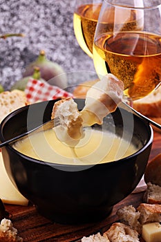 Gourmet Swiss fondue dinner on a winter evening with assorted cheeses on a board alongside a heated pot of cheese fondue with two