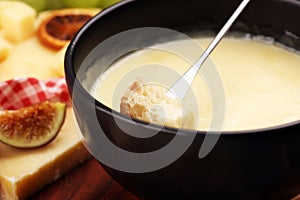 Gourmet Swiss fondue dinner on a winter evening with assorted cheeses on a board alongside a heated pot of cheese fondue with two