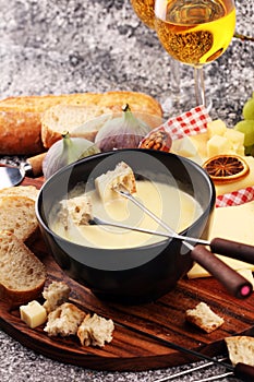 Gourmet Swiss fondue dinner on a winter evening with assorted cheeses on a board alongside a heated pot of cheese fondue with two