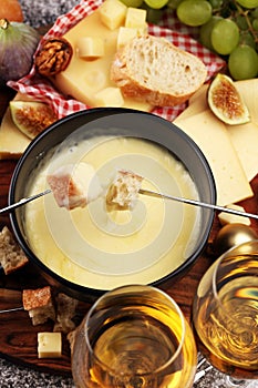 Gourmet Swiss fondue dinner on a winter evening with assorted cheeses on a board alongside a heated pot of cheese fondue with two