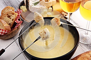 Gourmet Swiss fondue dinner on a winter evening with assorted cheeses on a board alongside a heated pot of cheese fondue with two