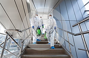 Government workers in protective suits making disinfection of stairs photo