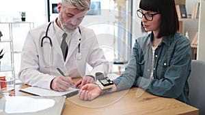 GP applying pulse oximeter on patient's wrist at clinic