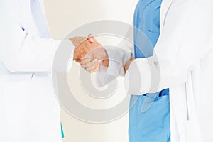 GP doctor shakes hand with surgical doctor.