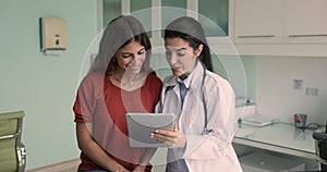 GP using tablet explain illness anamnesis to female patient