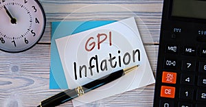 GPI INFLATION - words on a white sheet on the background of a calculator, alarm clock and pen