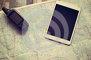 GPS navigator and tablet are on the paper map