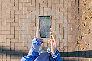 GPS. A woman& x27;s hand holds a smartphone with online maps application. Close-up. View from above. The concept of