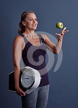 Grab hold of a healthier lifestyle. Studio shot of an attractive mature woman throwing an apple and holding a