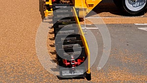 Grabbing grain from asphalt surface by scrapers of conveyor grain loader