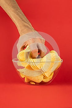 Grabbing potato chips from a glass bowl. Male hand greedily take