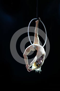 Graceful aerial acrobat doing her performance with a hoop isolated on black