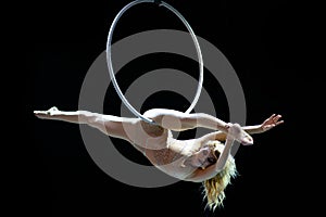 Graceful aerial acrobat doing her performance with a hoop isolated on black