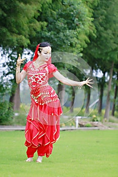 Graceful Asian Chinese belly dancer dancing on grass