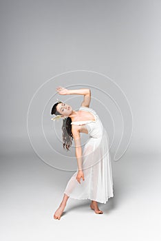 Graceful, attractive ballerina in white dress dancing