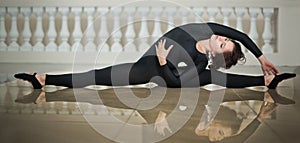 Graceful ballerina doing the splits on the marble floor. Gorgeous ballet dancer performing a split on glossy floor
