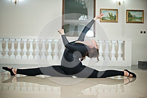 Graceful ballerina doing the splits on the marble floor. Gorgeous ballet dancer performing a split on glossy floor