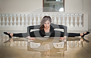 Graceful ballerina doing the splits on the marble floor. Gorgeous ballet dancer performing a split on glossy floor