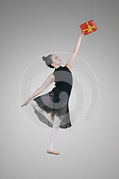 Graceful ballerina lifting a Christmas gift