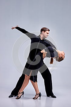 Graceful ballerina and male partner dancing elements of ballroom or modern ballet in studio.
