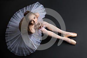 Graceful ballerina sitting on the floor