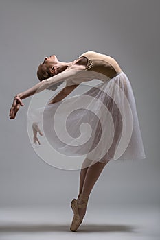 Graceful ballerina standing on toes bending the