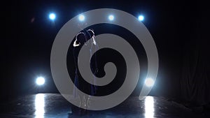 Graceful ballet dancer shows modern ballet over spotlights. Slow motion.