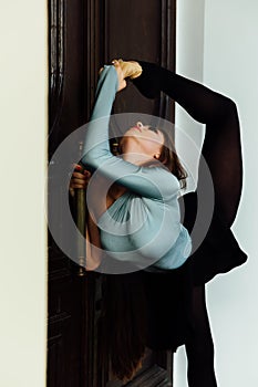 Graceful beautiful girl ballerina posing on the street of the vintage theater wood door.