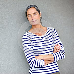Graceful beauty. Portrait of an attractive mature woman in casualwear standing against a gray wall.