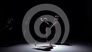 Graceful contemporary dance of four dancers on black, shadow, slow motion