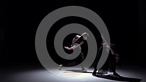 Graceful contemporary dance of two dancers on black, shadow, slow motion