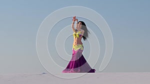 Graceful dancer against the sky dancing belly dance in a brilliant outfit