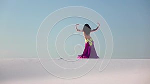 Graceful dancer against the sky dancing belly dance in a brilliant outfit. Slow motion